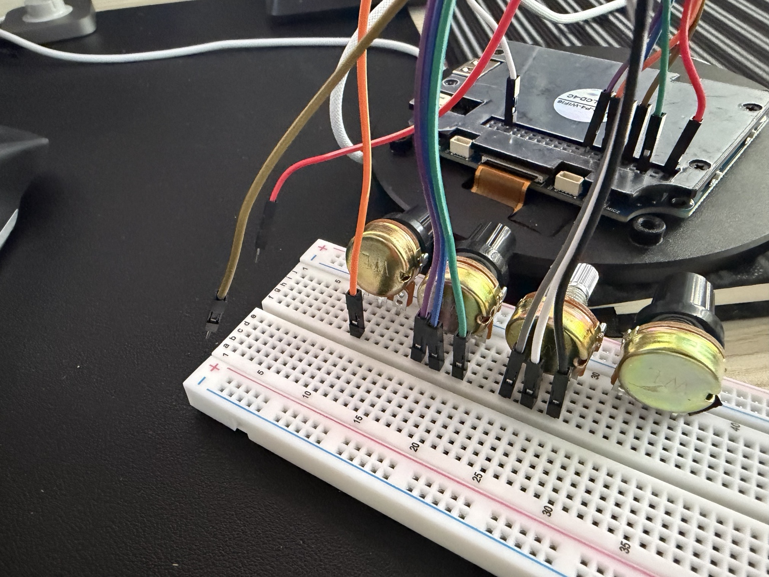 Breadboard with four rotary controls wired to the round display