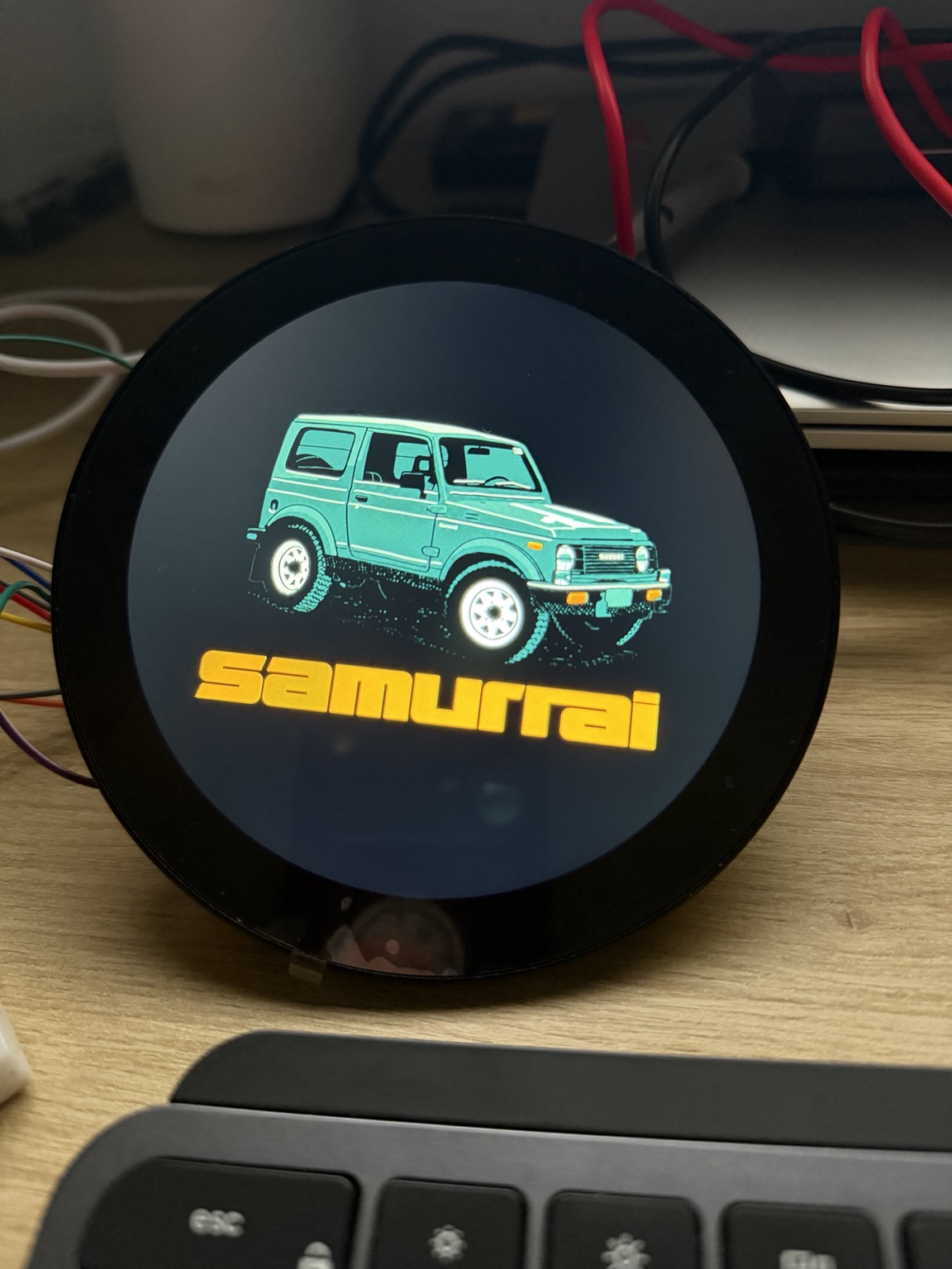 Round digital display showing a turquoise Suzuki Samurai boot graphic